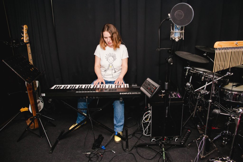 Anastazja z Mariupola siedzi i gra na keyboardzie w studiu nagraniowym